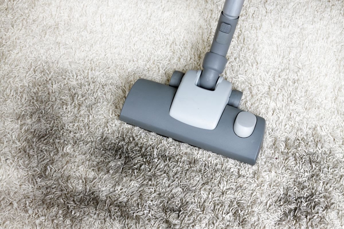 A vacuum cleaner in action, removing dirt from a patterned carpet.