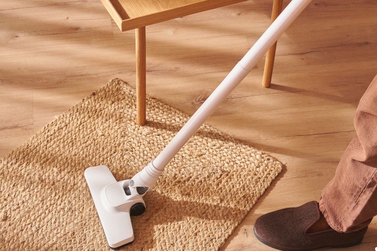 A person vacuuming a rug, demonstrating household cleaning and maintenance.
